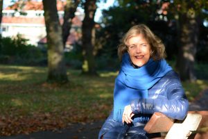 Een vrouw zit op een bankje in het park. Het laatste zonlicht in de herfst tovert licht en schaduweffecten op haar gezicht.