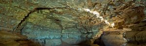 Een ondergrondse grot met prachtig gesteente, waarin door een spleet in de rots licht naar binnen valt